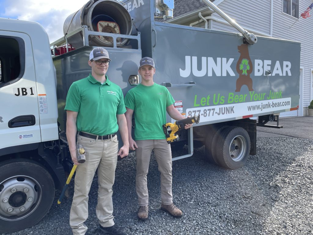 Junk removal professionals standing in front of their truck