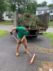 Junk Bear team member clearing away yard debris during a landscaping project